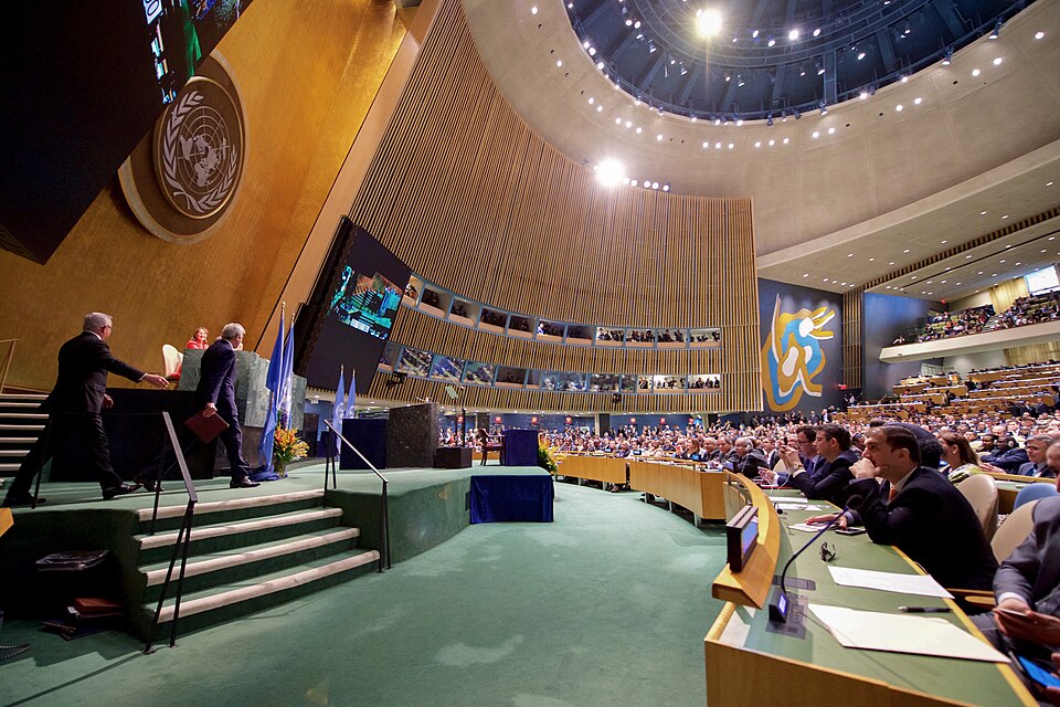 U.S. Secretary of State John Kerry walks onstage before he addressed delegates and signed the COP21 Climate Change Agreement on Earth Day, April 22, 2016, at the United Nations General Assembly Hall in New York, N.Y. [State Department photo/ Public Domain]