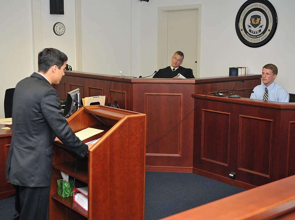 Justin Hebert, left, a senior at Kaiserslautern High School and lead prosecutor, questions Caleb Chastain, also a KHS senior, as he takes the stand in the role of the Casey Jones, the defendant, during a mock trial held at the Warren J. Argue Courtroom on Kleber Kaserne May 4. Looking on was Col. Da