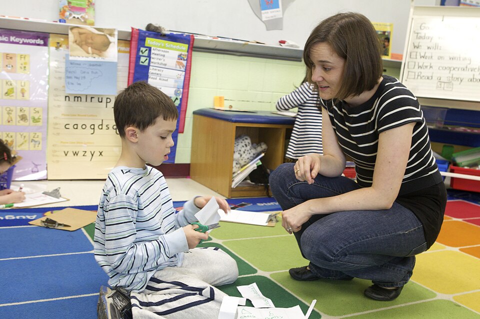 teacher kneeling to instruct student