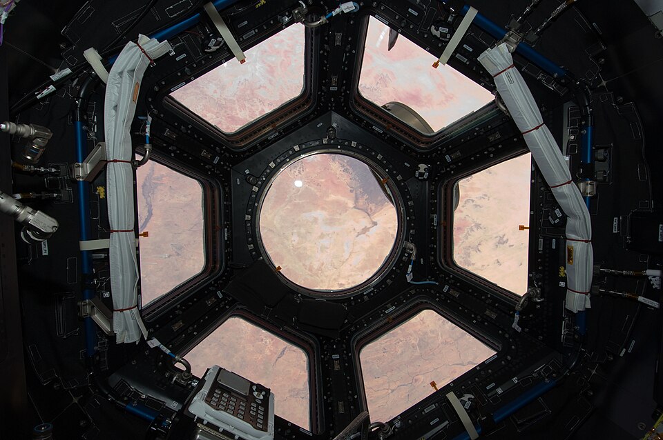 International space station module Cupola with its protective shutters open.
NASA description from source:

ISS022-E-066972 (17 Feb. 2010) --- This image is the first taken through a first of its kind "bay window" on the International Space Station, the seven-windowed Cupola. The image shows the Sah
