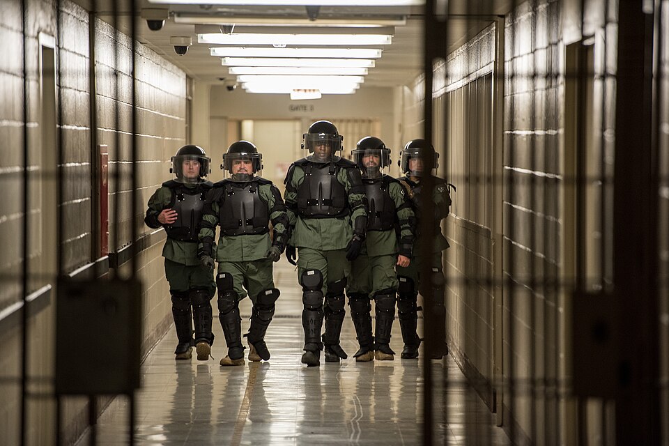 An ERO SRT team walks through a detention facility in riot gear.