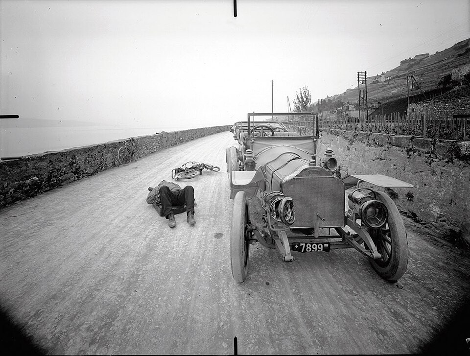 Black and white photograph, taken on the scene of an accident by criminologist Rodolphe Archibald Reiss. According to Olivier Robert, archivist at University of Lausanne, it is possibly a staged reconstitution of the accident. The location is Route de Lavaux, near Rivaz. Date: 15 May 1913.