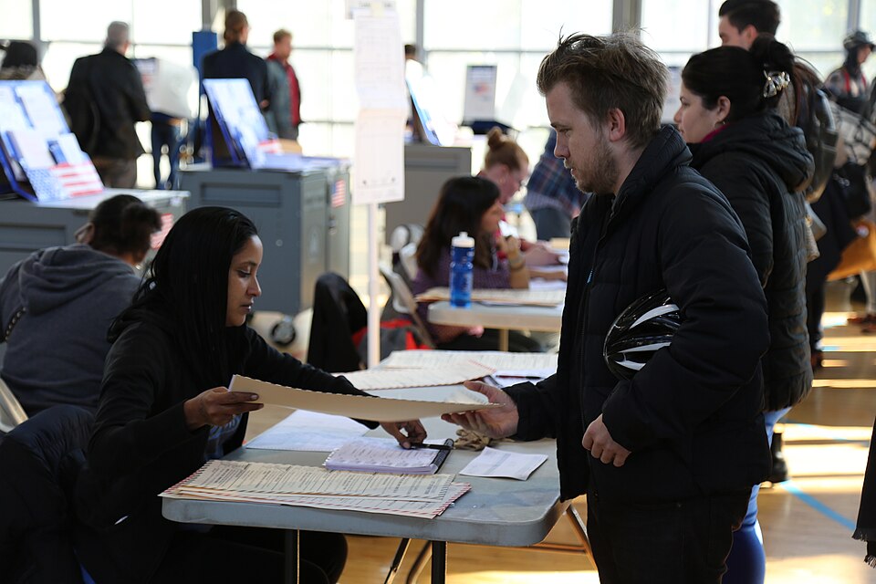 Voter gets his ballot before voting in presidential election at polling station in New York City, Nov. 8, 2016. (Photo: R. Taylor / VOA)