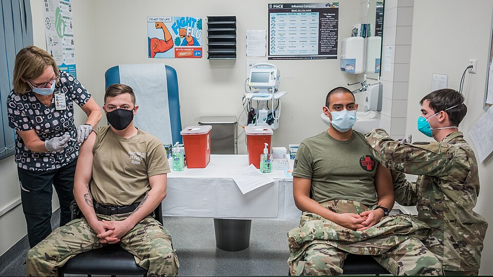 WIESBADEN, Germany – The first two COVID-19 vaccines at the Wiesbaden Army Health Clinic were administered simultaneously to Sgt. Hunter Gonzales (left), military police, and Sgt. Luis Pineda (right), NCO of the Soldier Ready Medical Center, by nurses Julia Crissinger and Sgt. Eron Johnson Dec. 30, 