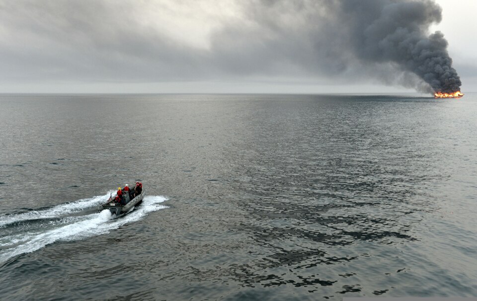 U.S. Sailors assigned to the guided missile destroyer USS William P. Lawrence (DDG 110) survey the area surrounding a burning vessel for possible survivors March 11, 2013, while transiting the Strait of Hormuz. The William P. Lawrence was deployed to the U.S. 5th Fleet area of responsibility to prom