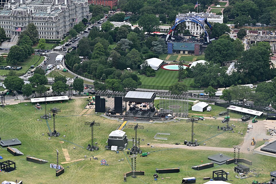 A stage is being set up on the Elipse, there is a sign by it that says UFC Freedom 250. Behind it, on the south lawn of the White House is the UFC Freedom 250 arena, also in the process of being set up. The Elipse, Washington, DC.