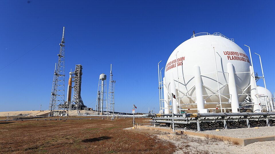 NASA’s Artemis II SLS (Space Launch System) rocket with the Orion spacecraft and launch abort system atop stands vertical in the background with a 1.4-million-gallon, 83-foot-wide, liquid hydrogen sphere in the foreground at Launch Complex 39B at NASA’s Kennedy Space Center in Florida on Tuesday, Fe