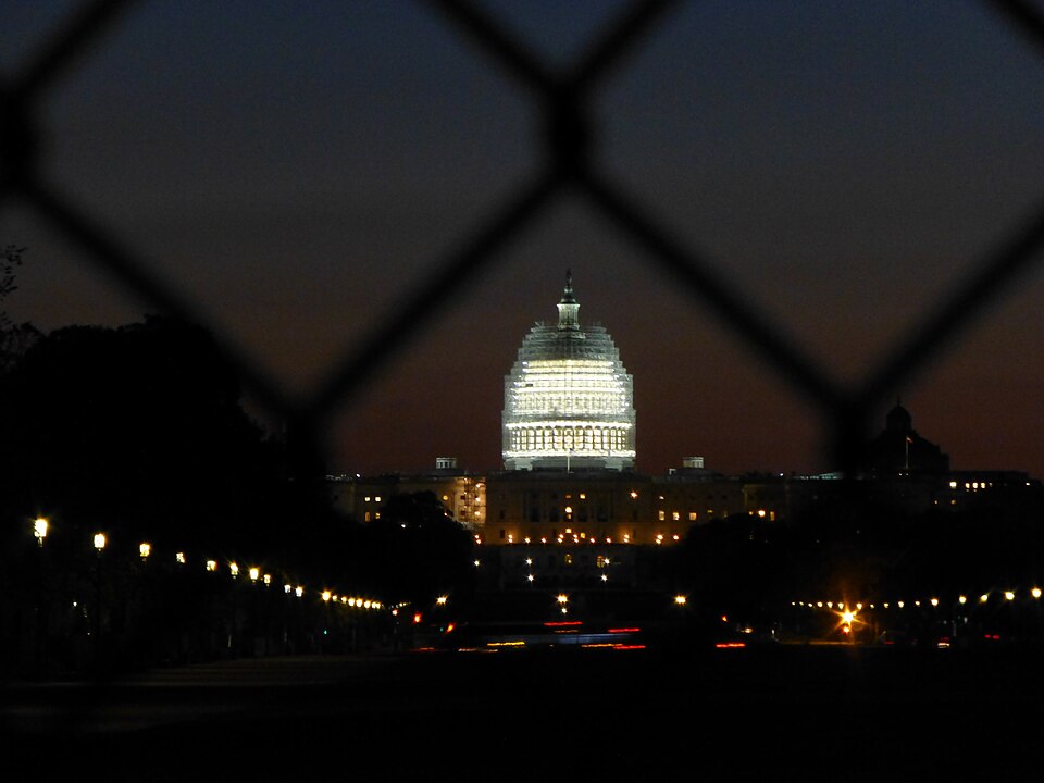 United States Capitol Building shot through a fence at dawn.