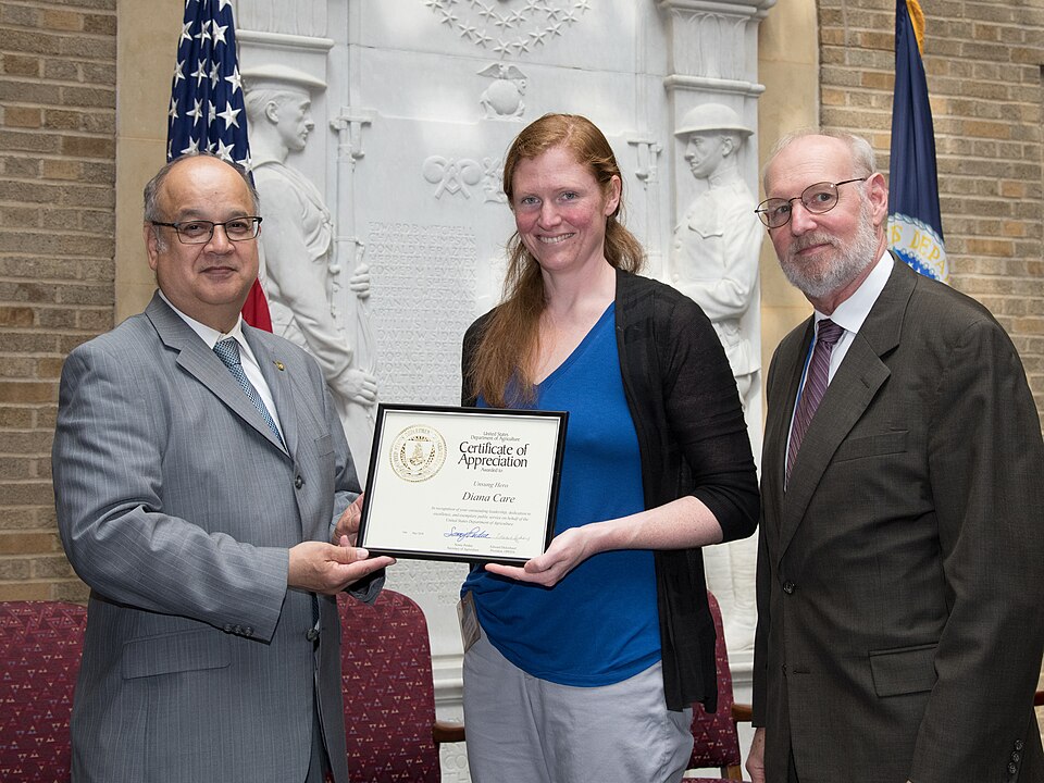 U.S. Department of Agriculture (USDA) Food Safety and Inspection Service (FSIS) Public Health Veterinarian Supervisor Dianna Care is awarded a certificate of appreciation at the 2018 USDA Unsung Hero Awards Program, on May 10, 2018, in Washington, D.C. Presenting the award is Organization of Profess