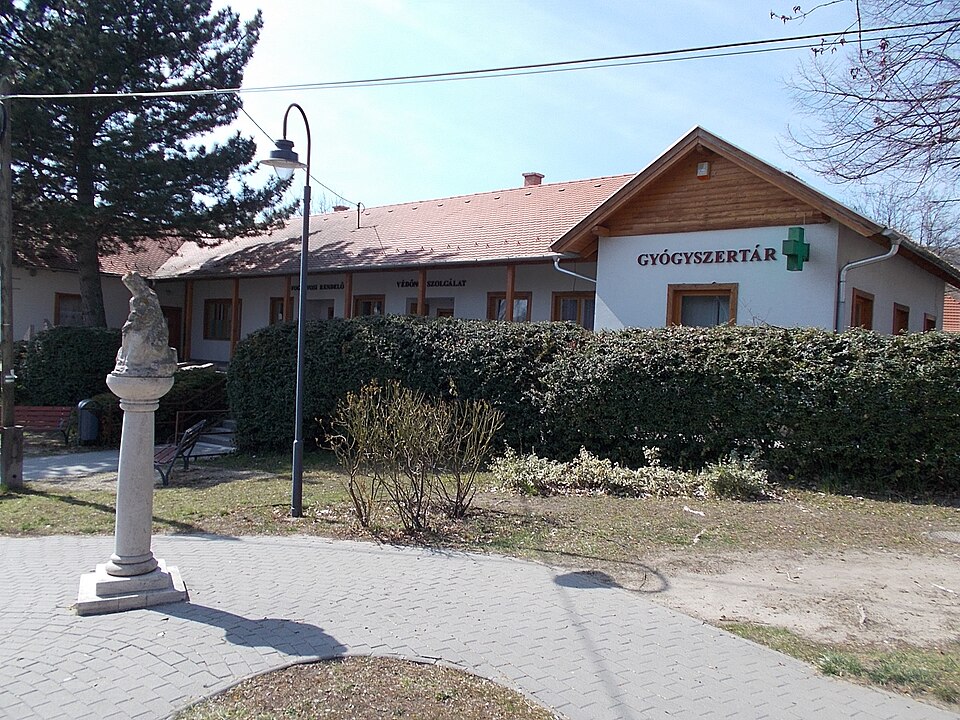 On left astatue of Elizabeth of Hungary /German: Heilige Elisabeth von Thüringen/ by György Markolt and Katalin Gémes (2010 works circa one and half meter limestone column with a same size statue on its top) Elisabeth in sitting position hold a sitting ill (or dead) men - At back is a Health Center 