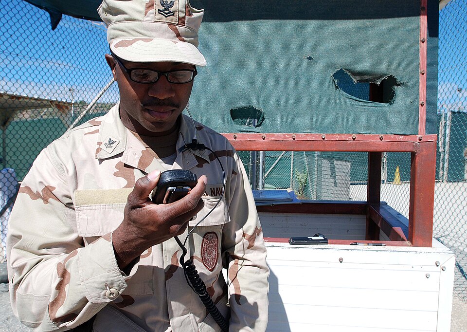 Navy Petty Officer 2nd Class Corenzo King, an operations specialist with Joint Task Force Guantanamo's Navy Expeditionary Guard Battalion, receives a call on his radio while on watch at Camp 4, part of JTF Guantanamo, Dec. 7, 2009. The NEGB provides a portion of the guard force inside Joint Task For