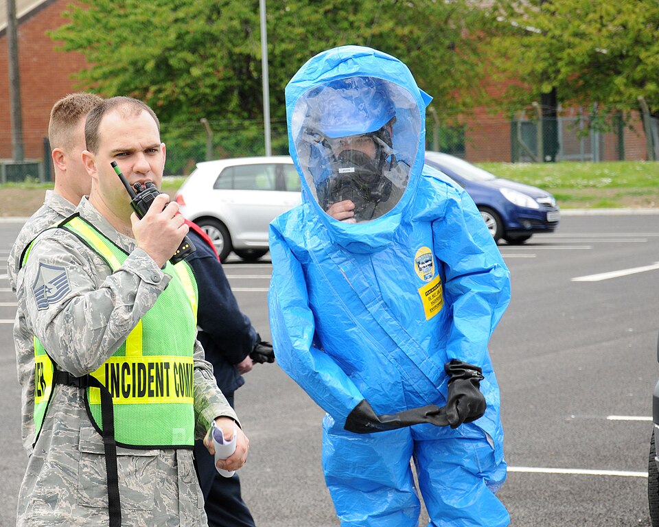 U.S. Air Force Master Sgt. Robert Peterson, left, 100th Civil Engineer Squadron Fire Department assistant chief from Hudson, Mass., uses a radio to communicate with his team during a hazardous material exercise May 6, 2014, on RAF Mildenhall, England. The base exercises regularly to ensure emergency