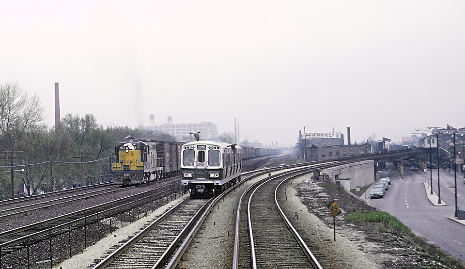 Before October 28, 1962 the Lake St. "L" ran at street level next to the C&amp;NW's elevated embankment through far western Chicago and Oak Park after it dismounted its "L" structure above Lake Street.  It was slow running with lots of grade crossings.  On that date the trains shifted to new tracks 