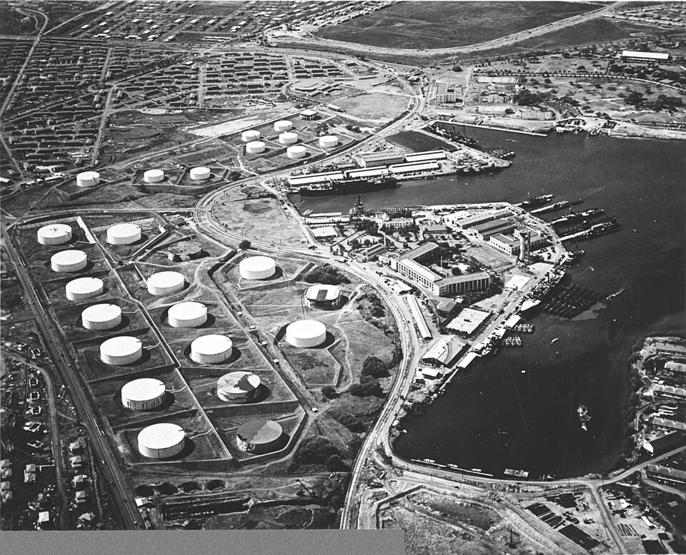 Aerial view of the Pearl Harbor submarine base (right center) with the fuel farm at left, looking south on 13 October 1941.
Among the 16 fuel tanks in the lower group and ten tanks in the upper group are two that have been painted to resemble buildings (topmost tank in upper group, and rightmost tan