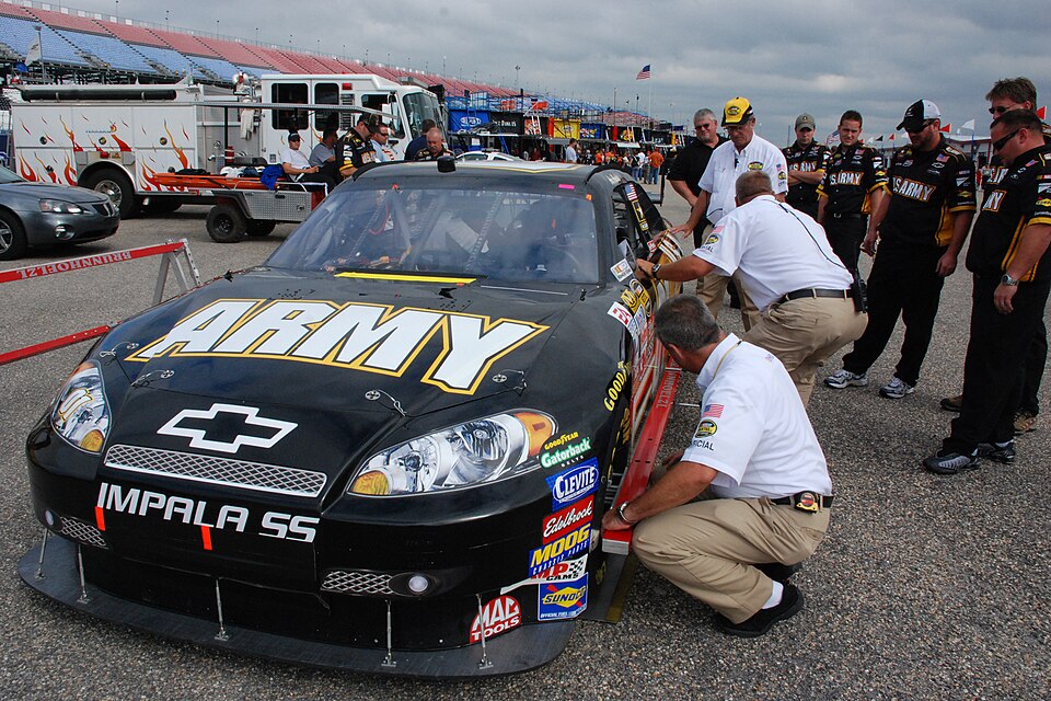 TALLADEGA, Ala. -- The No. 01 Army car gets inspected in the garage Oct. 6 while one of the fire trucks and a three-man crew sits in the background watching the action in the garage. John Piccuito, J.R. Suddarth and Tech. Sgt. Jimmy Reed, Eglin Air Force Base firefighters, are among a group of firef