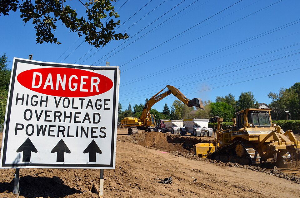A danger sign reminds contractors to be wary of high-voltage power lines as crews excavate a haul route next to a levee along the American River’s north bank in Sacramento, Calif., Aug. 28, 2012. The haul route will be used for loading material into trucks at a lower and safer height, keeping constr