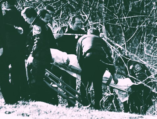 Atlanta Constitution press image of police officers removing the body of a victim of the Atlanta Child Murders from a wooded area in DeKalb County. Direct link here