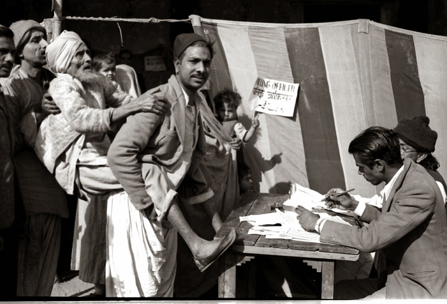 A blind old man being carried towards a polling booth by his son, to help him to cast his vote, near a polling station in Jama Masjid area in Delhi.
