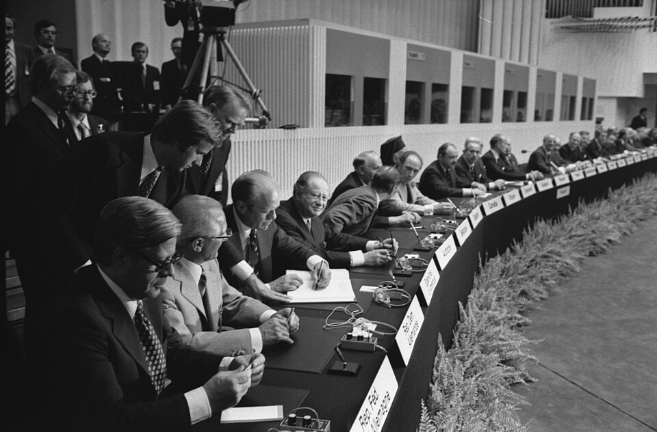 President Gerald Ford signs the Final Act of the Conference on Security and Cooperation in Europe as it is passed among European leaders for signature in  Finlandia Hall.