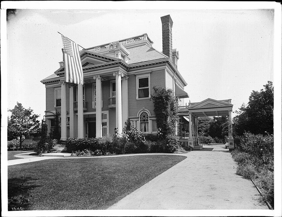 J.D. Hooker residence, Adams Boulevard and Hope Street, ca.1900-1905
Photograph of the palacial Greek revival residence of J.D. Hooker on Adams Boulevard at Hope Street, ca.1900-1905. Large 45-star American flag hangs from the peak of the two-story columned portico. A covered drive is to the right o