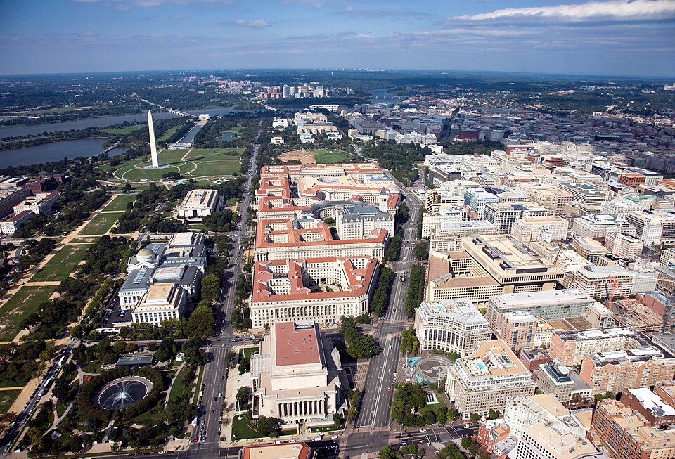 Aerial view of Pennsylvania Avenue (center right) and the Federal Triangle (center) – facing west towards Arlington County, Virginia –  in Washington, D.C.  Visible landmarks include the National Archives Building (center bottom), Constitution Avenue (center left), the National Museum of Natural His