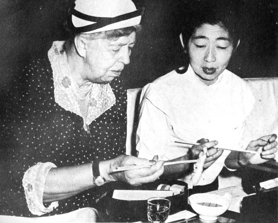 Eleanor Roosevelt uses chopsticks as she lunches with her interpreter, Yoko Matsuoka, at the Japanes