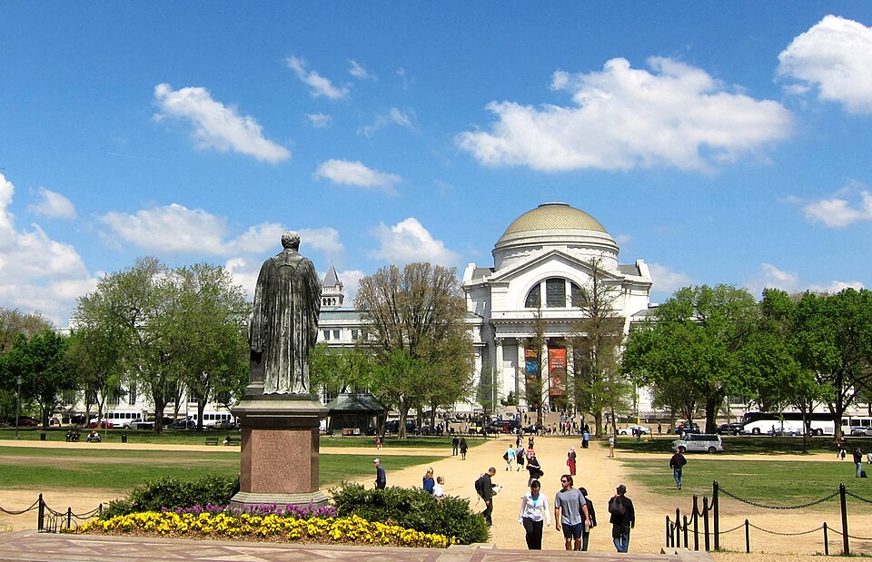 Facing north across the National Mall in Washington, D.C., as viewed from the entrance to the Smithsonian Institution Building.  The statue honoring Joseph Henry is in the foreground; the National Museum of Natural History is in the background; and the Old Post Office Pavilion's tower is visible in 