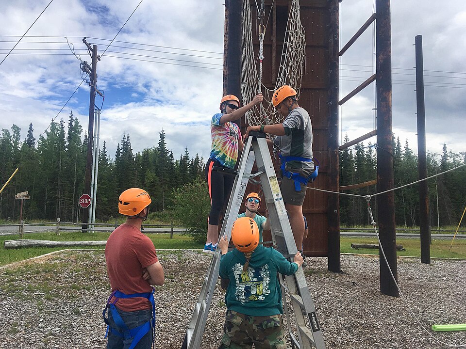 Spc. Karissa Price, a healthcare specialist with the Alaska National Guard’s medical detachment, secures Sgt. Elijah Gutierrez, a team leader with C Company, 297th Long Range Surveillance Squadron, Alaska Army National Guard, to the giant swing element of the Encourage, Encounter and Experience Chal