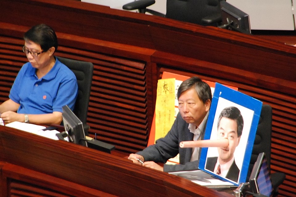 ​支联会主席、工党立法会议员李卓人（右）在行政长官答问大会展示讽刺梁振英说谎的照片。