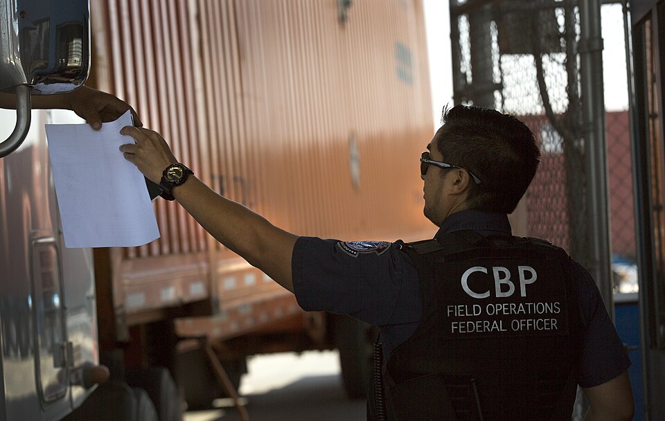A U.S. Customs and Border Protection officer hands documents back to a truck driver as he monitors an inbound checkpoint at the Otay Mesa, Calif., port of entry, June 23, 2016. CBP Photo by Glenn Fawcett