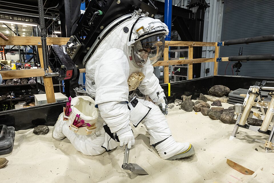A NASA crew member practices using lunar tools to collect geology samples at NASA’s Johnson Space Ce