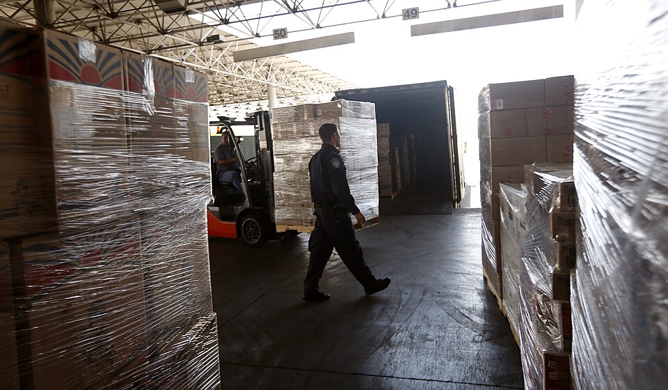 A U.S. Customs and Border Protection officer walks through pallets of offloaded imported goods prior to inspection at the Otay Mesa, Calif., port of entry, June 23, 2016. CBP Photo by Glenn Fawcett