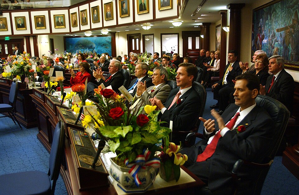 Rep. David Coley, R-Marianna, right, joins with colleagues in the flower-filled House chamber while they applaud a moment in Gov. Bush's State-of-theState speech on opening day of the Legislature March 8, 2005.