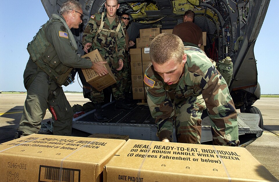 U.S. Army Pvt. Raef Hardin (right) and Spc. Jade Harris (second from left) help crew chief Staff Sgt. Brian Ogle (left) load hundreds of meals, ready to eat and water onto a CH-47 Chinook helicopter at Ellington Field, Texas, on Sept. 27, 2005. Department of Defense units are mobilized as part of Jo