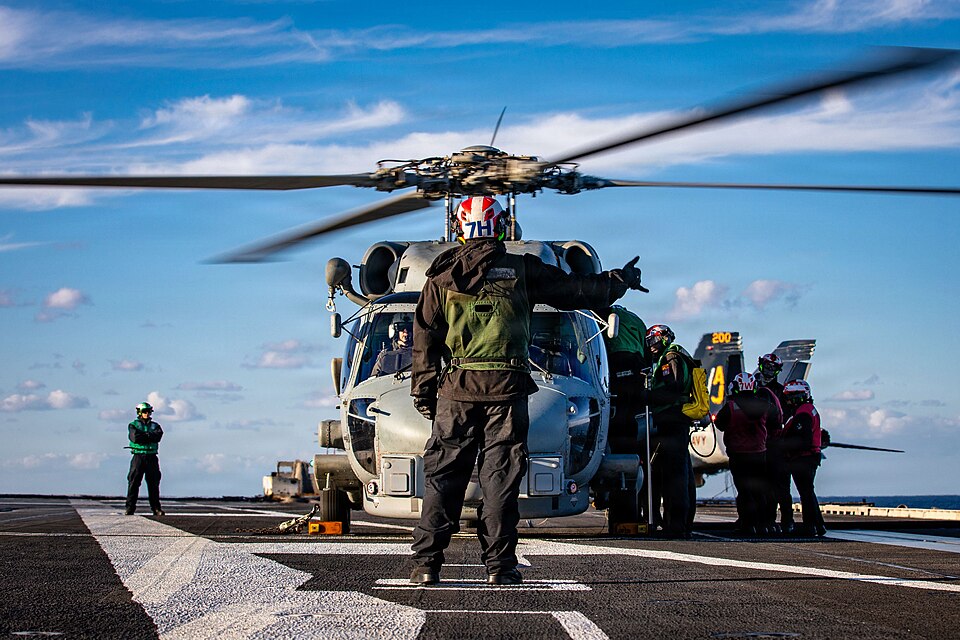 A U.S. Sailor signals to an MH-60R Sea Hawk helicopter, attached to Helicopter Maritime Strike Squadron 70, on the flight deck of the world's largest aircraft carrier, USS Gerald R. Ford (CVN 78), while supporting Operation Epic Fury, Feb. 28, 2026. (U.S. Navy photo)