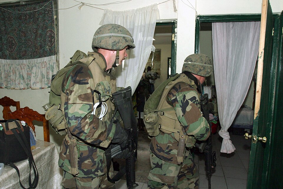 US Marine Corps (USMC) Marines assigned to 3/8 Kilo Company, 1st Platoon, 2nd Marine Division, armed with 5.56mm M16A2 rifles, clear a room during a predawn raid on an apartment complex in Port-Au Prince, Haiti. The complex was believed to be the location where Marines had been taking sporadic fire 