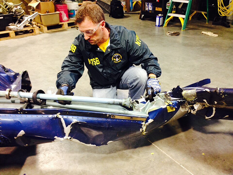 Aviation Safety Investigator Josh Cawthra examines the tail rotor drive shaft of the accident helicopter in Seattle.