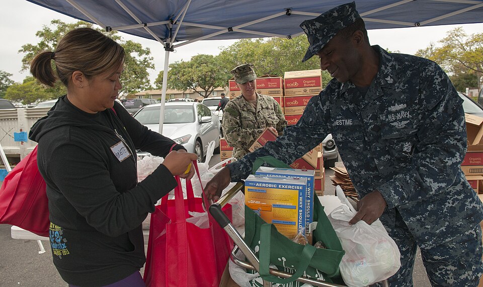 Logistics Specialist 1st Class Jonas Estime helps a shopper with groceries during the Neighborhood Exchange Food Bank Distribution event at the Murphy Canyon Armed Services YMCA (ASYMCA) Headquarters in San Diego. Sailors volunteered with the ASYMCA, who partnered with the San Diego Food Bank, to pr