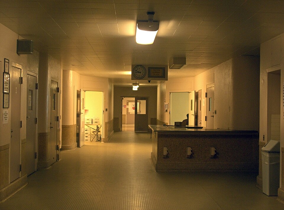 Hallway with rooms originally used for patient care, old hospital at Los Angeles County+USC Medical Center, after the building was closed to patient care, approximately 2012. The 'table' on the right side was a nurses' station.