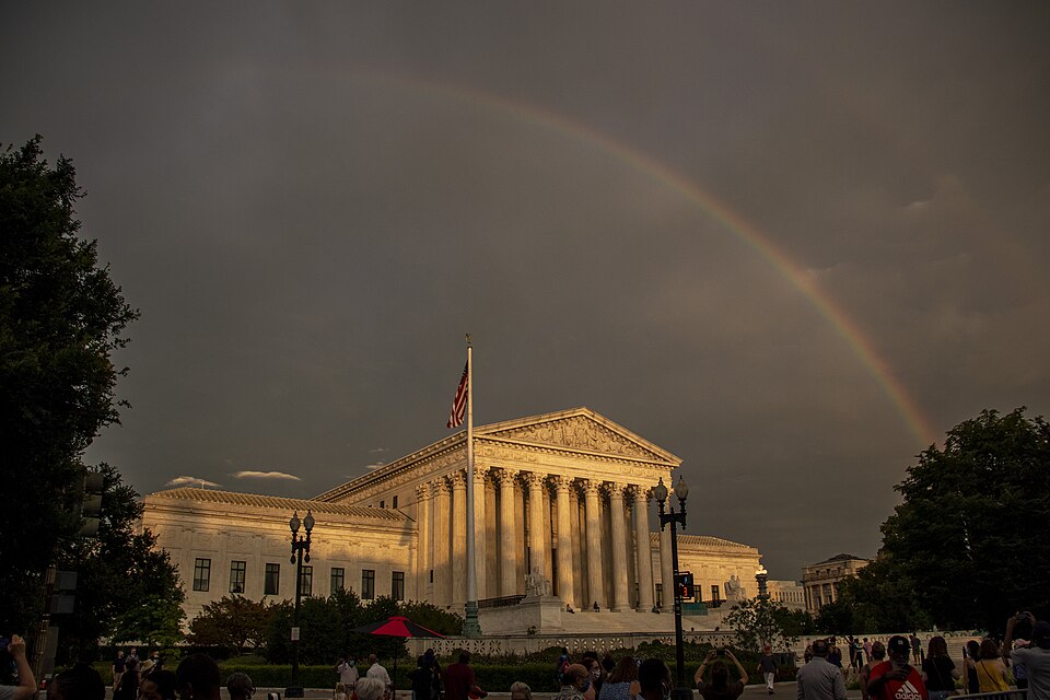 A colorful rainbow arches over a building with tall vertical columns holding up the peaked roof and an American flag in front of the building.
A double rainbow arches over the U.S. Supreme Court building in Washington D.C.
Keywords: SCOTUS; Washington DC