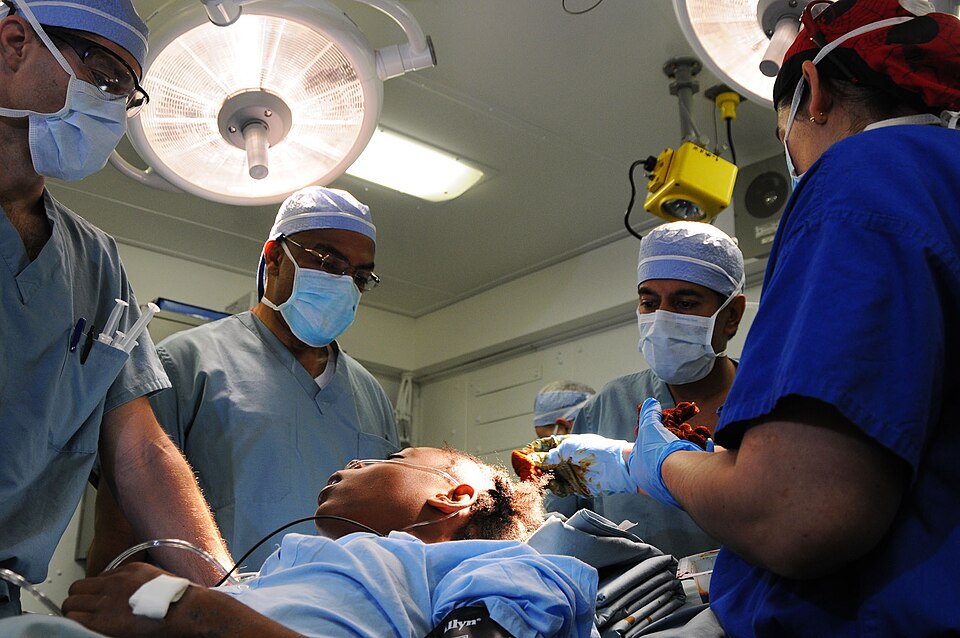 PORT-AU-PRINCE, Haiti (Jan. 18, 2010) Cmdr. Jerry Berman, left, a Navy surgeon, Dr. Henri R. Ford, Los Angles Pediatric Hospital Surgeon-in-Chief originally from Haiti, Dr. Sanjay Gupta, a CNN medical correspondent and practicing neurosurgeon, and Lt. Cmdr. Kathryn Berndt, a Navy surgeon, prepare a 