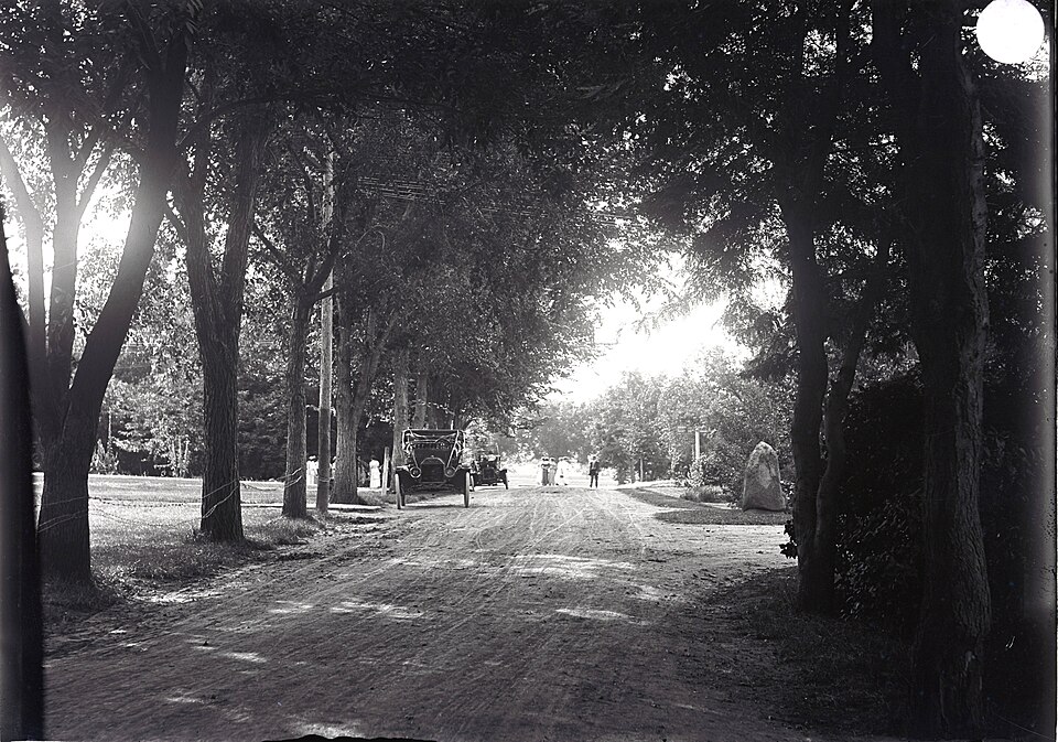 On the campus looking west from the Spring. The scene shows two cars with no license plates (pre 191