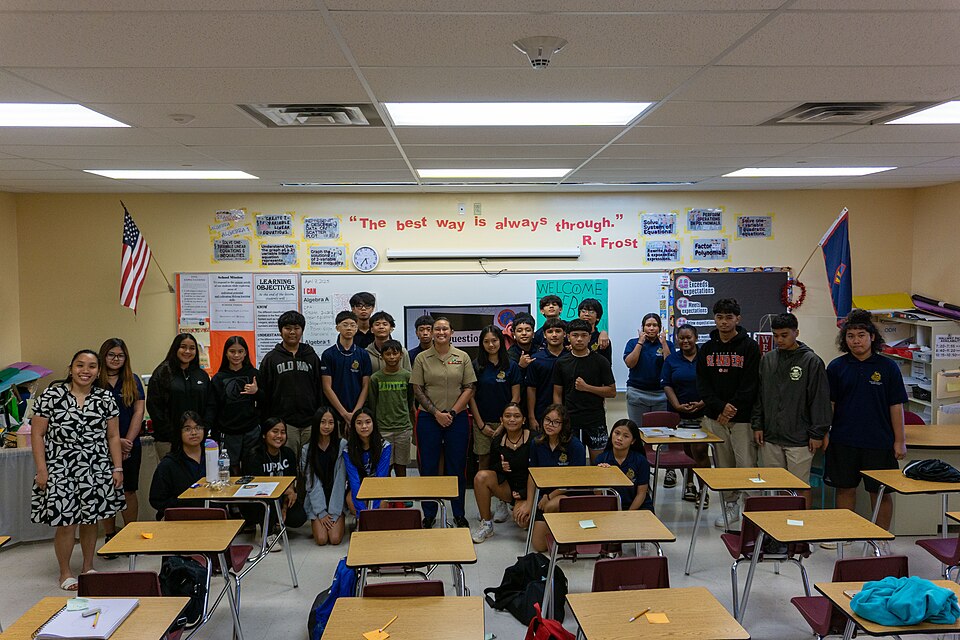 U.S. Marine Corps Staff Sgt. Jessica Suarez-Pierce, manpower chief, Marine Corps Base Camp Blaz, poses with a F.B. Leon Guerrero Middle School class after a career day presentation at Okkodo High School, Dededo, Guam, April 4, 2025. Staff Sgt. Suarez-Pierce explained the different career paths possi