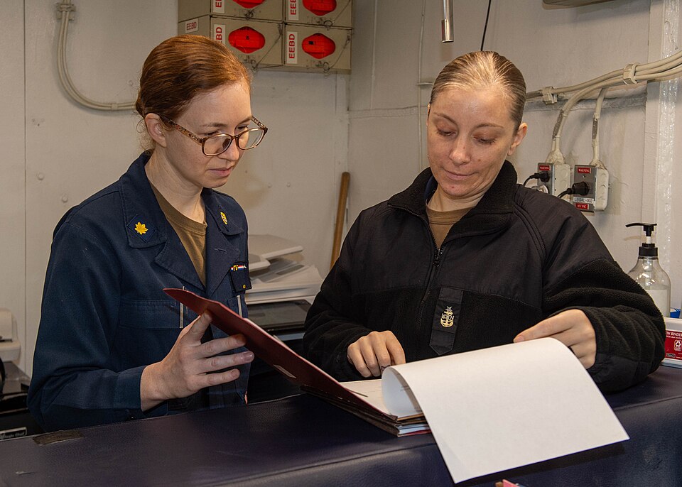 PHILIPPINE SEA (Nov. 7, 2023) Lt. Cmdr. Autumn Gibo, left, from Belpre, Ohio, and Senior Chief Legalman Briana Ridlon, from San Mateo, California, review legal documents in the legal office aboard the U.S. Navy’s only forward-deployed aircraft carrier, USS Ronald Reagan (CVN 76), in the Philippine S