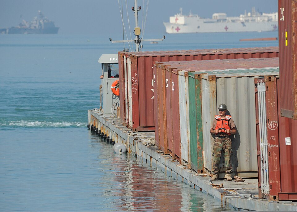 U.S. Navy Boatswain's Mate 1st Class Jason Fullenkamp, with Amphibious Construction Battalion 2, unloads a container via the Joint Logistics Over-the-Shore (JLOTS) system in Port-au-Prince, Haiti, Feb. 8, 2010. The system uses a floating causeway to move cargo containers to the shore. The JLOTS syst