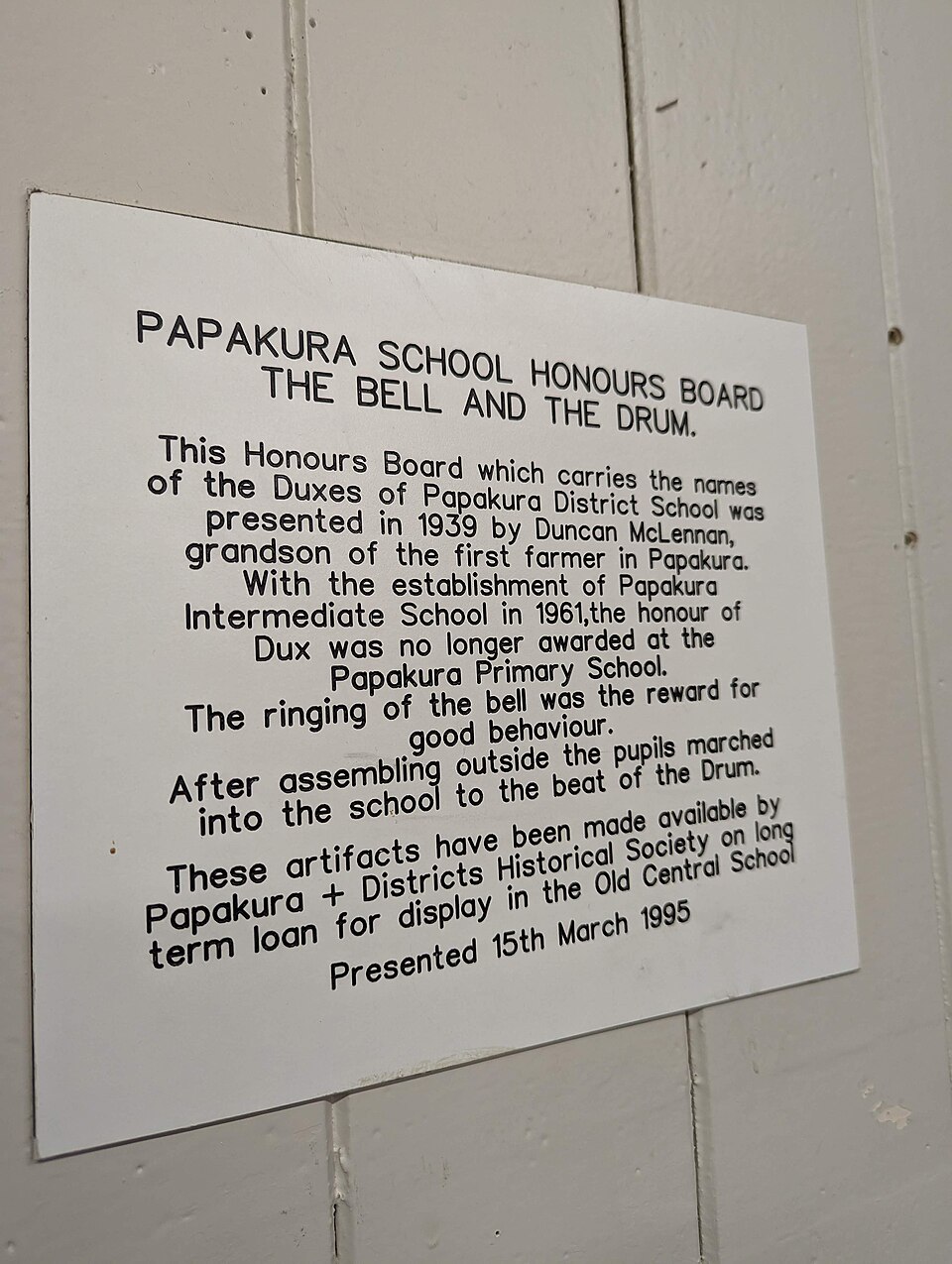 This sign, located in the Papakura Old School Meeting Hall, reads:
Papakura School Honours Board
The Bell and the Drum
This Honours Board which carries the names of the Duxes of Papakura District School was presented in 1939 by Duncan Mclennan, grandson of the first farmer in Papakura.
With the esta