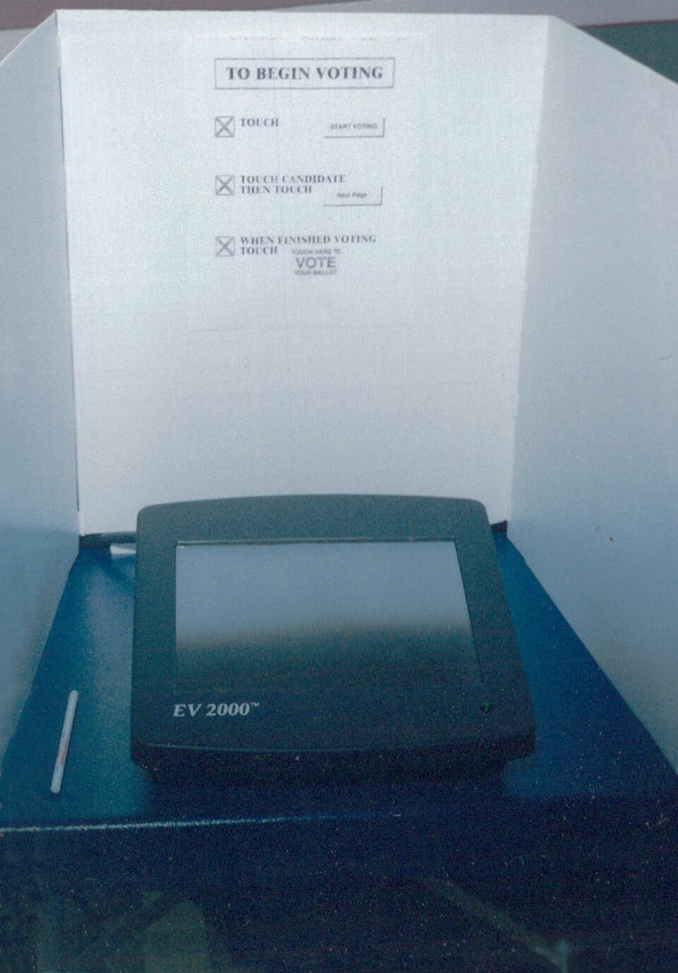 A Fidlar Doubleday (formerly Fidlar and Chambers) EV 2000 DRE voting machine in a voting booth with voting posted voting instructions.  The machine was on with a ballot display on-screen when this photo was taken.  The narrow viewing angle of the screen offered significant privacy to the voter.  Thi