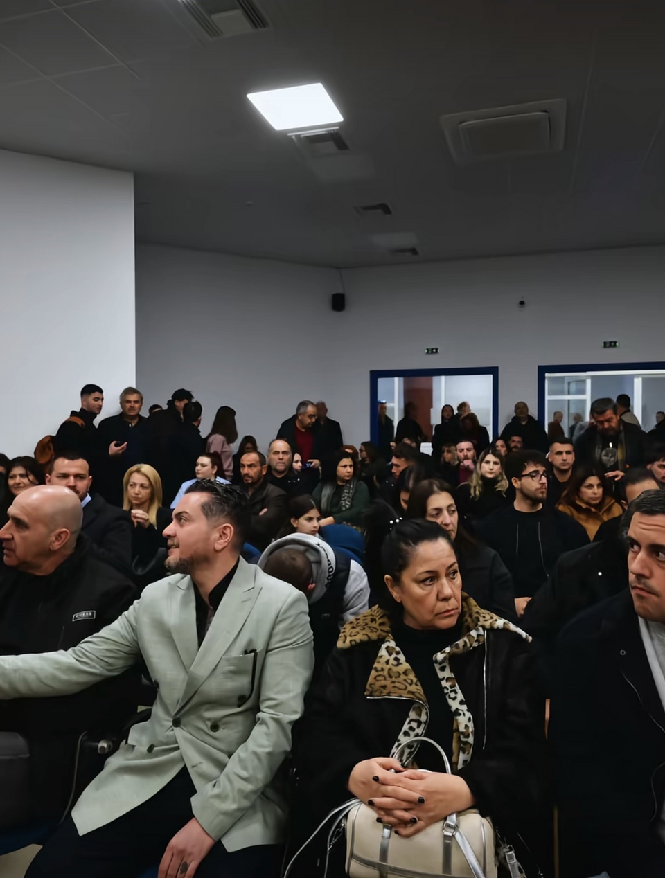A general view of the courtroom showing the audience during the opening of judicial proceedings related to the Tempi train crash of 28 February 2023. The audience includes relatives of victims, lawyers, and members of the public attending the hearing in Greece on 23 March 2026.