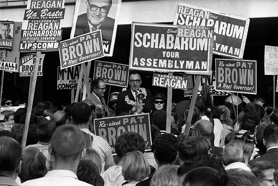 Governor Edmund G. (Pat) Brown surrounded by crowd and campaign signs in West Covina, California