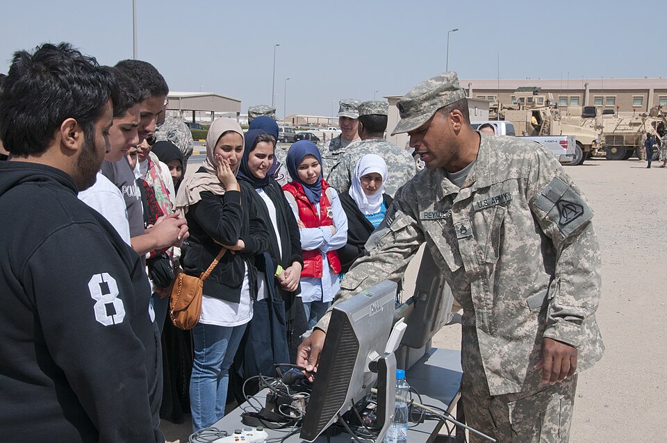 Staff Sgt. Rodney Reynolds, Joint Robotics Program shop foreman and native of Chicago, shows Kuwaiti students the control interface for several robots used by explosive ordinance disposal here, March 10. The students are part of a U.S. Department of State funded Access Microscholarship English Progr